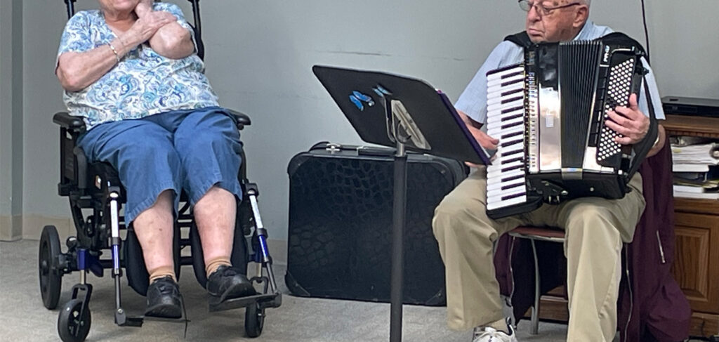 Gene plays the accordion while Val watches