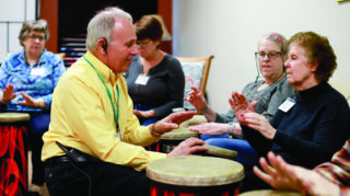 Open Circle Adult Day Services members participating in a therapeutic drum circle with staff guidance.