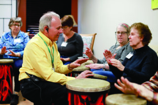 Open Circle Adult Day Services members participating in a therapeutic drum circle with staff guidance.