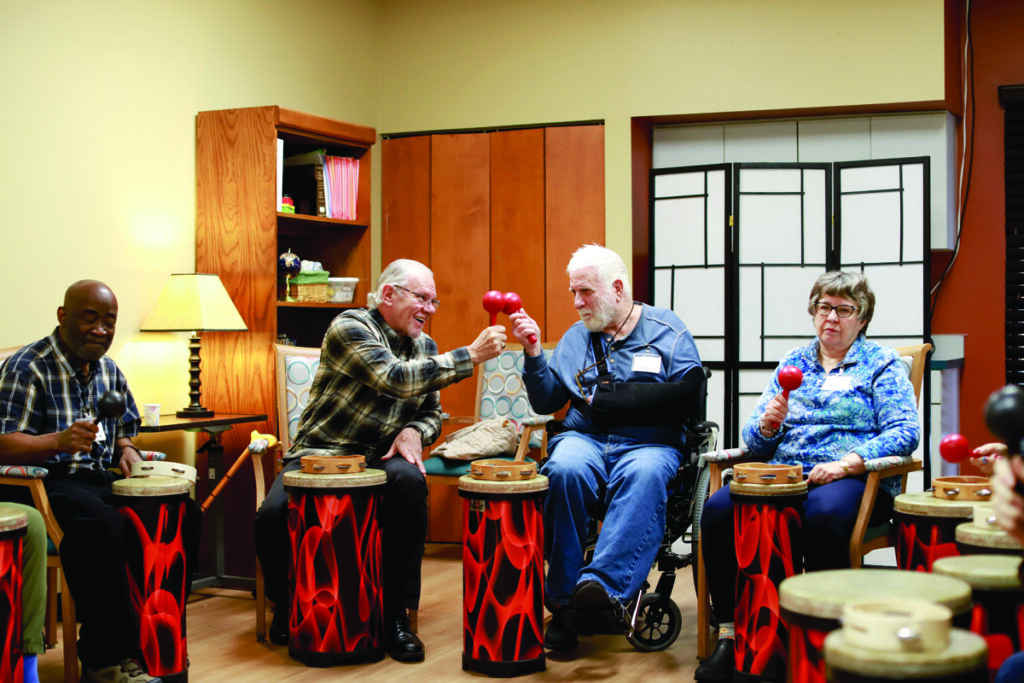 Members of Open Circle Adult Day Services enjoying a drum circle with percussion instruments and group interaction.